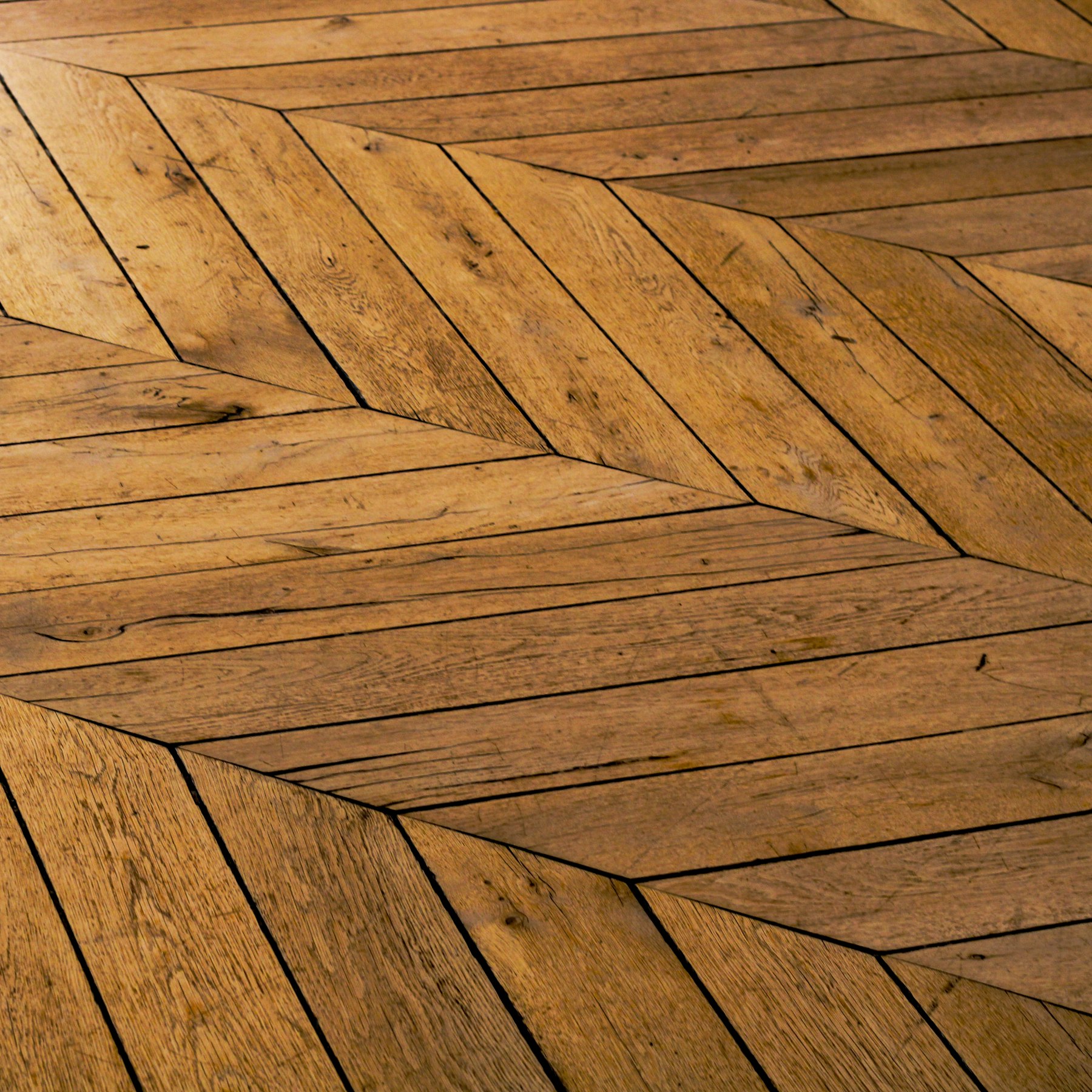 Herringbone hardwood flooring laid in a tight, even pattern